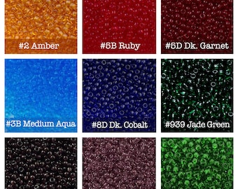 May include: A grid of nine square panels displaying small, translucent glass seed beads in various colors labeled #2 Amber, #5B Ruby, #5D Dk. Garnet, #3B Medium Aqua, #8D Dk. Cobalt, #939 Jade Green, #6C Dk. Amethyst, #6 Lt. Amethyst, and #7B Med. Green.
