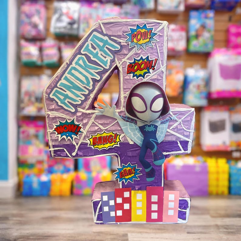 May include: A large, purple number four pi&ntilde;ata with the name "ANDREA" in light blue. A Spider-Gwen figure is attached to the front. Comic book sound effects like "POW!" and "BOOM!" are also included. The base features colorful building cutouts.