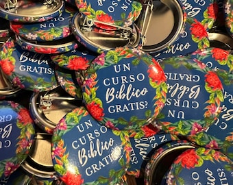 May include: A close-up of a pile of colorful round buttons with a floral design and the text "UN CURSO BIBLICO GRATIS?" in Spanish. The buttons are made of metal and have a pin on the back.