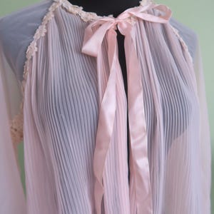 May include: A vintage pale pink pleated robe, featuring a lace trim and a satin ribbon tie. The sheer fabric creates a soft, romantic look. The robe is displayed on a black mannequin. The measurements are in centimeters.