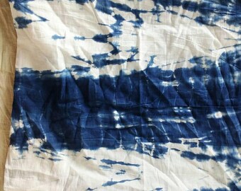 May include: A white fabric with a blue tie-dye pattern. The fabric is folded and has a wrinkled texture.
