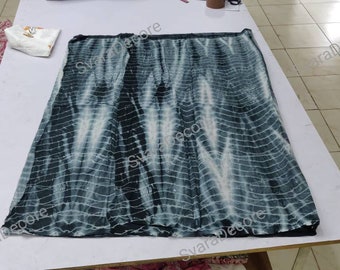 May include: A black and white tie-dye fabric with a grid pattern. The fabric is folded in half and laid flat on a white surface.