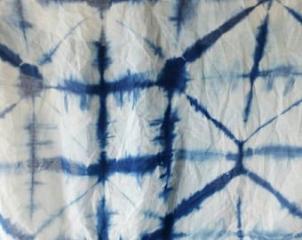 May include: A white fabric with a blue tie-dye pattern. The pattern is a grid of intersecting lines, creating a geometric design.