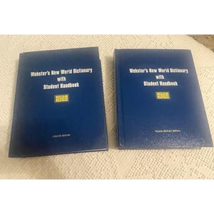 Peut inclure: Deux dictionnaires bleus, "Webster's New World Dictionary with Student Handbook," sont présentés. L'un est l'édition concise, l'autre l'édition pour jeunes. Les deux livres arborent le logo "SIU".
