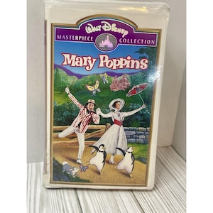 Może przedstawiać: Zapieczętowana kaseta VHS z filmu Disneya "Mary Poppins" z kolekcji Masterpiece. Okładka przedstawia kolorową ilustrację postaci, w tym Mary Poppins, Berta, pingwiny i motyle, na tle malowniczej scenerii.