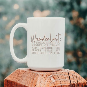 May include: White ceramic mug with a brown inscription that reads "Wanderlust: A strong desire to wander or travel and explore the places that set your soul on fire."