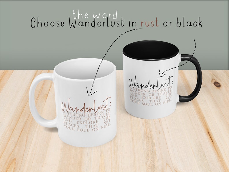May include: Two white coffee mugs with black handles. One mug has the word "Wanderlust" in black lettering and the other mug has the word "Wanderlust" in rust colored lettering. Both mugs have the definition of wanderlust printed below the word.