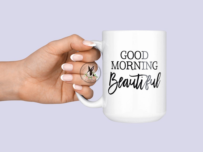 Peut inclure: Une tasse &agrave; caf&eacute; en c&eacute;ramique blanche avec du texte noir qui dit "Good Morning Beautiful".