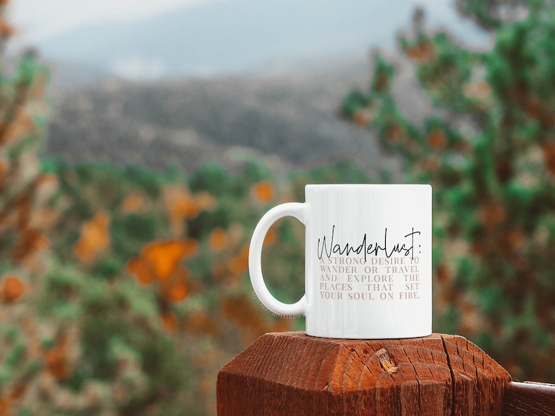 May include: White ceramic mug with a black and gray design that reads "Wanderlust: A strong desire to wander or travel and explore the places that set your soul on fire."