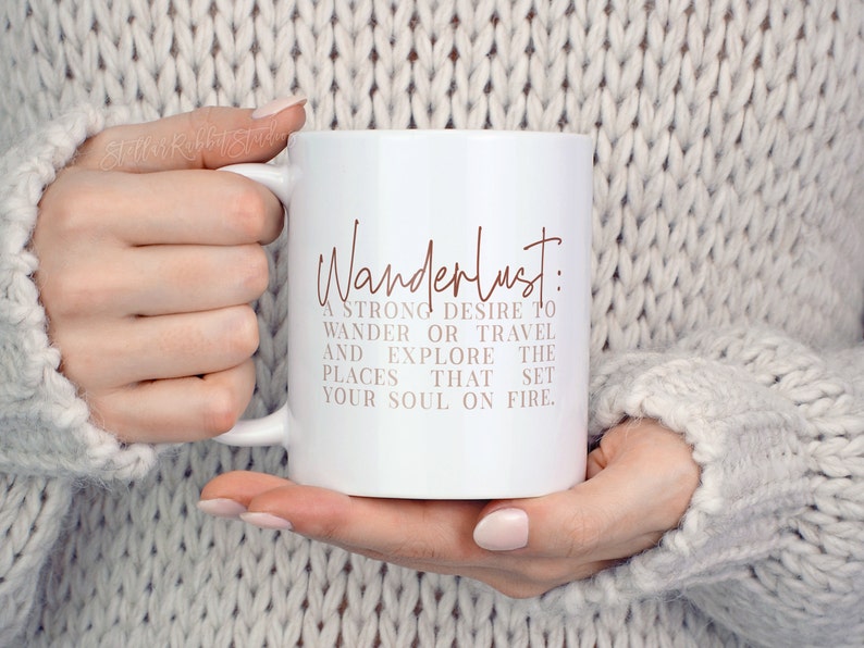 May include: White ceramic mug with a brown inscription that reads "Wanderlust: A strong desire to wander or travel and explore the places that set your soul on fire."
