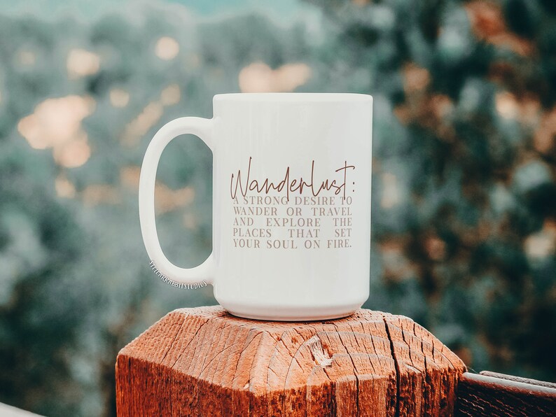 May include: White ceramic mug with a brown inscription that reads "Wanderlust: A strong desire to wander or travel and explore the places that set your soul on fire."