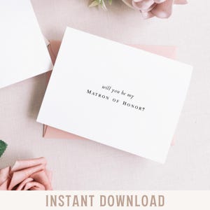 May include: A white card with the text "will you be my MATRON OF HONOR?" in black, resting on a pink envelope. The words "INSTANT DOWNLOAD" are at the bottom of the image. Soft pink flowers are in the background.