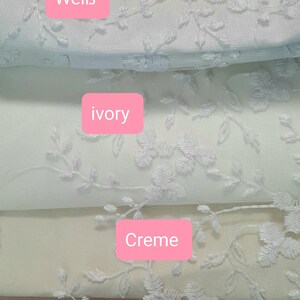 May include: Close-up of several fabric swatches in various shades of white, cream, and sand. Each swatch features an embroidered floral design. The swatches are labeled with the colors: Wei&szlig;, ivory, Creme, and Sand.