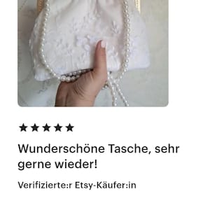 Bewertun einer Kundin - Weiße Clutch mit floraler Stickerei, goldenem Verschluss und Perlenkette als Henkel. Der Text auf dem Bild lautet "Wunderschöne Tasche, sehr gerne wieder!" und "Verifizierte:r Etsy-Käufer:in".