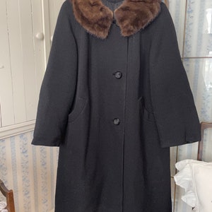May include: A black wool coat with a large brown fur collar. The coat has a single button fastening and two pockets.