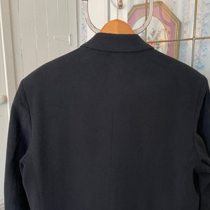 Puede incluir: Una chaqueta negra de dise&ntilde;o cl&aacute;sico. La chaqueta tiene cierre de un solo bot&oacute;n y solapa de muesca.