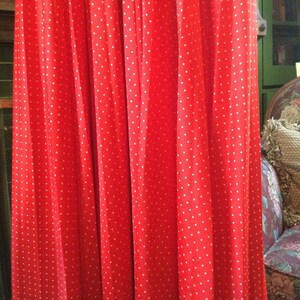 May include: Red pleated skirt with white polka dots. The skirt is made of a soft, flowing fabric and has a simple, elegant design.