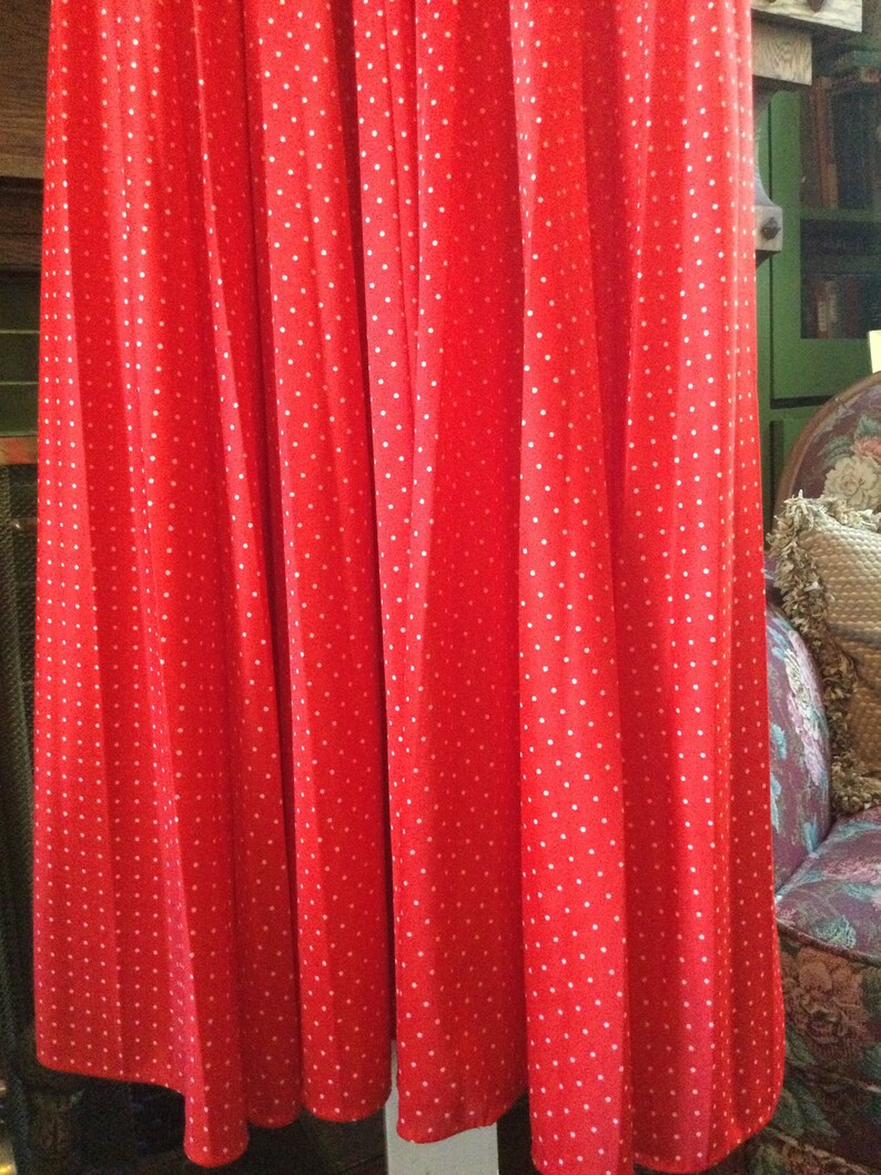 May include: Red pleated skirt with white polka dots. The skirt is made of a soft, flowing fabric and has a simple, elegant design.