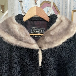 May include: A black curly fur coat with a large, white fur collar. The coat has a single button closure and a label that reads "Brunswick Furriers".