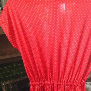 May include: A red dress with a white polka dot pattern. The dress has a gathered waist and short sleeves.