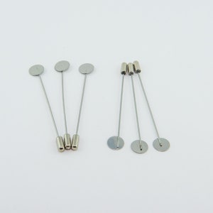 May include: A set of silver-toned hat pins with round heads. The pins are about 2 inches long and have a simple, elegant design.