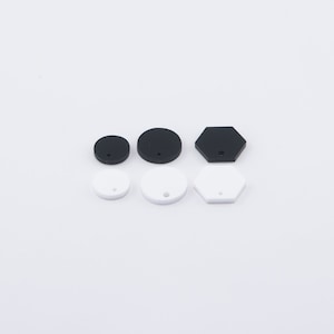 May include: Assortment of black and white round and hexagonal shapes with a hole in the center. These shapes are made of wood and can be used for crafting projects.