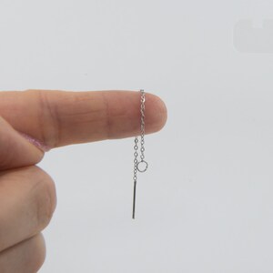 May include: A silver chain with a small circle charm and a straight bar pendant.