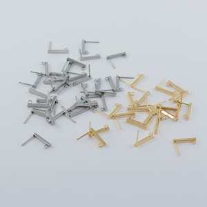 May include: A collection of gold and silver earring findings. The findings are rectangular in shape with a loop at the top and a post at the bottom.