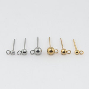 May include: Five pairs of earring findings with a small ball and a loop at the end. Two pairs are silver and three pairs are gold.