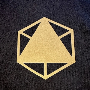 Pode incluir: Um desenho geométrico dourado sobre um fundo preto. O desenho é um hexágono com um triângulo dentro.