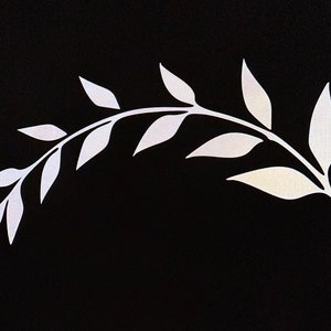 Op de afbeelding: Een wit silhouet van een bebladerde tak met meerdere bladeren op een zwarte achtergrond.