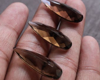 May include: Three teardrop-shaped smoky quartz gemstones in various shades of brown. The gemstones are faceted and have a glossy finish.