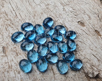 Pode incluir: Um grupo de pedras preciosas ovais de cor azul claro sobre uma superfície de madeira.