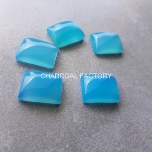 Könnte beinhalten: Fünf hellblaue quadratische Cabochon-Edelsteine. Die Edelsteine sind glatt und poliert.