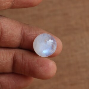 May include: A round, white moonstone cabochon with a blue sheen.