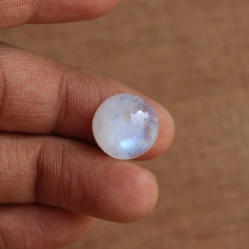 May include: A round, white moonstone cabochon with a blue sheen.