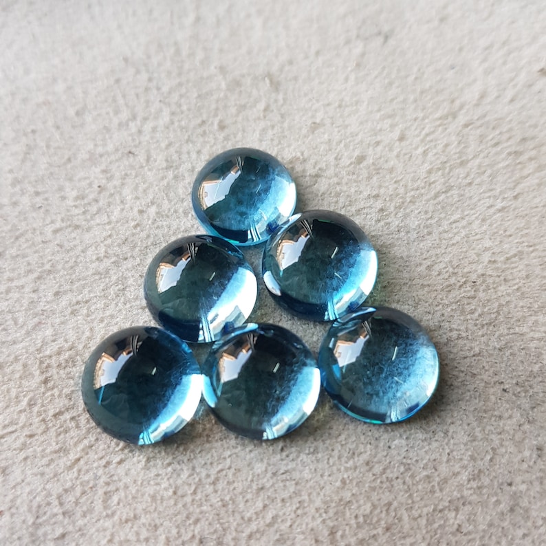 Op de afbeelding: Zes ronde, blauwe glazen stenen met een reflecterend oppervlak.