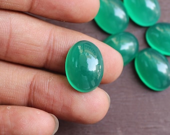May include: A collection of six oval-shaped green gemstones. The gemstones are smooth and polished, with a translucent appearance.