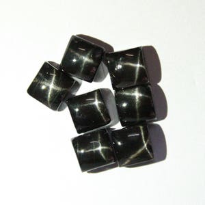 Puede incluir: Ocho piedras preciosas cabujón negras en forma de estrella con un patrón de estrella blanca. Las piedras están talladas en forma cuadrada.