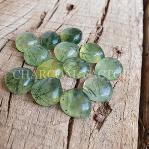 May include: A collection of green and yellow gemstone cabochons with a unique, sparkly, and translucent appearance. The stones have a natural, organic look and are perfect for jewelry making or crafting.
