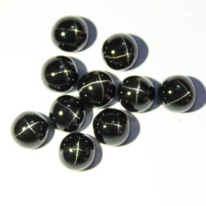 May include: Ten black star-shaped gemstones with a silver star in the center. The gemstones are round and have a smooth, polished surface.