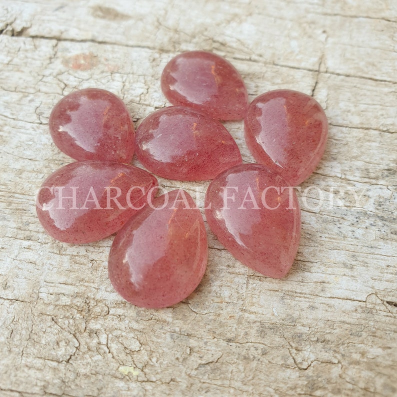 May include: Seven teardrop-shaped, translucent pink gemstone cabochons with a speckled appearance.
