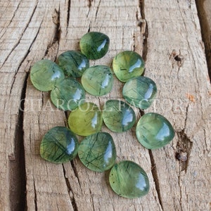 May include: A collection of green and yellow gemstone cabochons with a unique, striated pattern. The cabochons are heart-shaped and have a translucent appearance.
