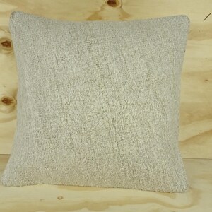 May include: A soft, off-white throw pillow with a textured, fuzzy surface.