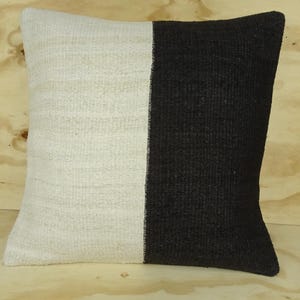May include: A white and black pillow with a woven texture. The pillow is rectangular and has a seam down the middle.