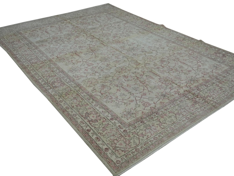 May include: A large, rectangular rug with an intricate floral pattern in shades of cream, beige, and muted red. The rug features a detailed border and a distressed, vintage appearance, suitable for living rooms or bedrooms.