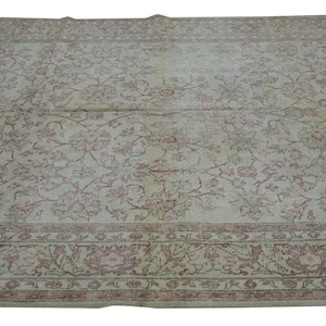 May include: A large, rectangular rug with an intricate floral pattern in shades of cream, pink, and brown. The rug features a detailed border with floral motifs. The overall design is vintage and elegant, suitable for a living room or bedroom.