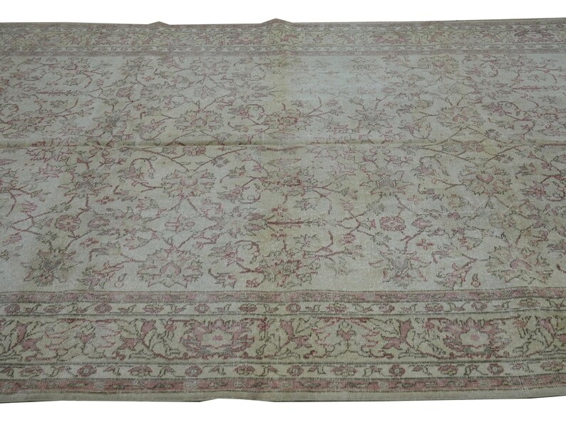 May include: A large, rectangular rug with an intricate floral pattern in shades of cream, pink, and brown. The rug features a detailed border with floral motifs. The overall design is vintage and elegant, suitable for a living room or bedroom.