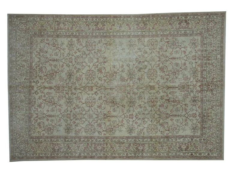 May include: Rectangular area rug with a floral pattern in shades of beige, light green, and muted red. The rug features a detailed border and an overall distressed appearance, suggesting a vintage style.