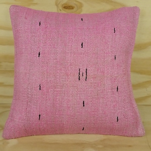 Peut inclure: Un coussin carré rose avec un tissage texturé. Le coussin présente une série de petits tirets verticaux noirs répartis sur la surface, avec un groupe de trois tirets au centre. Un élément de décoration pour la maison.